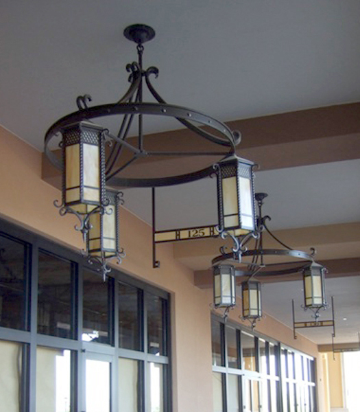 Two chandeliers composed of three lanterns attached to a metal ring, hanging in a row.