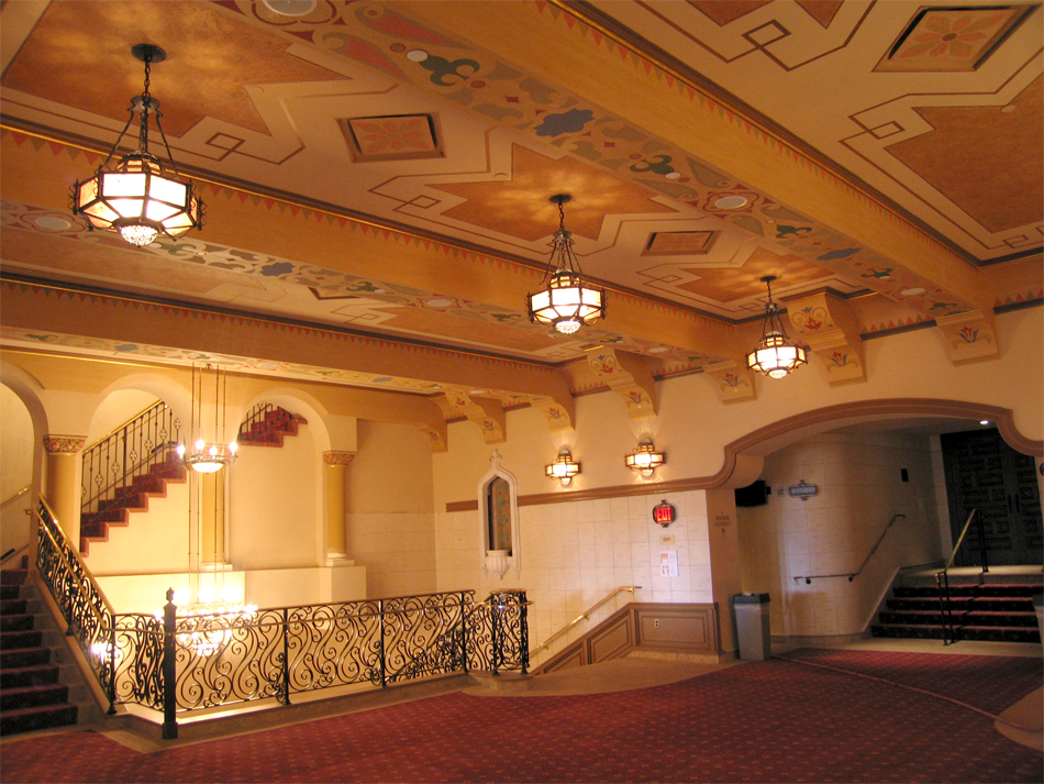 Three chandeliers hanging in a row from the ceiling of a second floor landing.