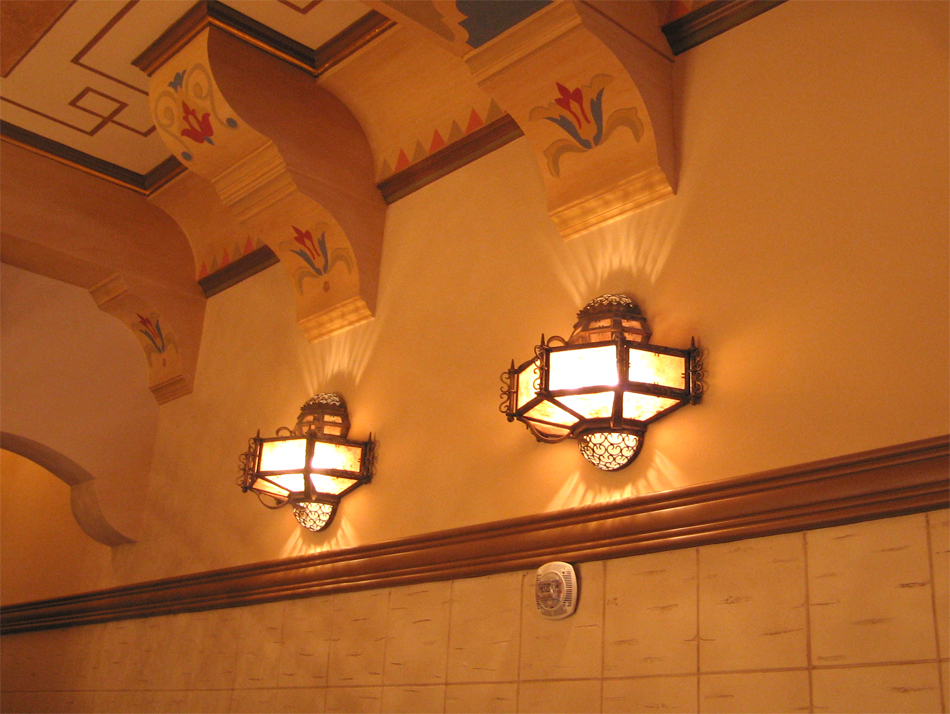 Two spanish style wall sconces illuminating a wall.