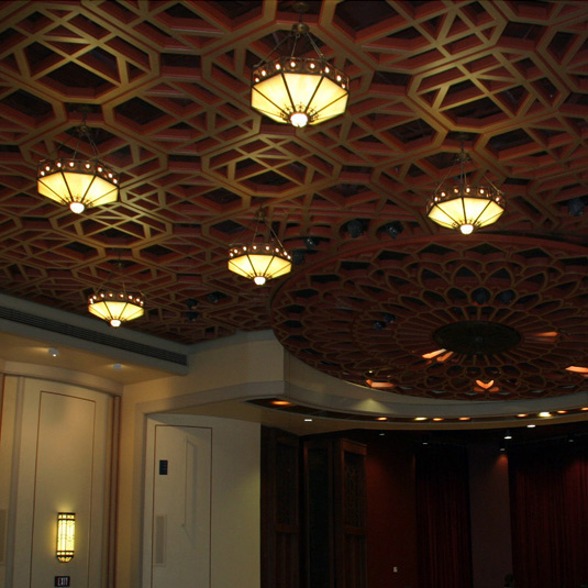 Five lanterns hanging from a geometrically patterned ceiling.