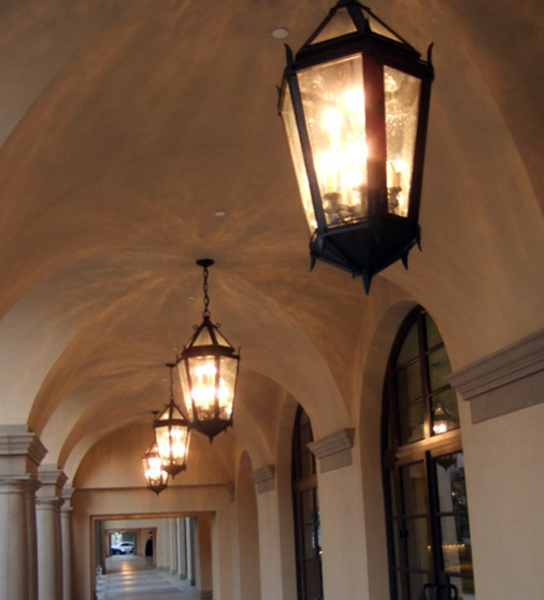 Close up of lanterns hanging from arches in hallway.