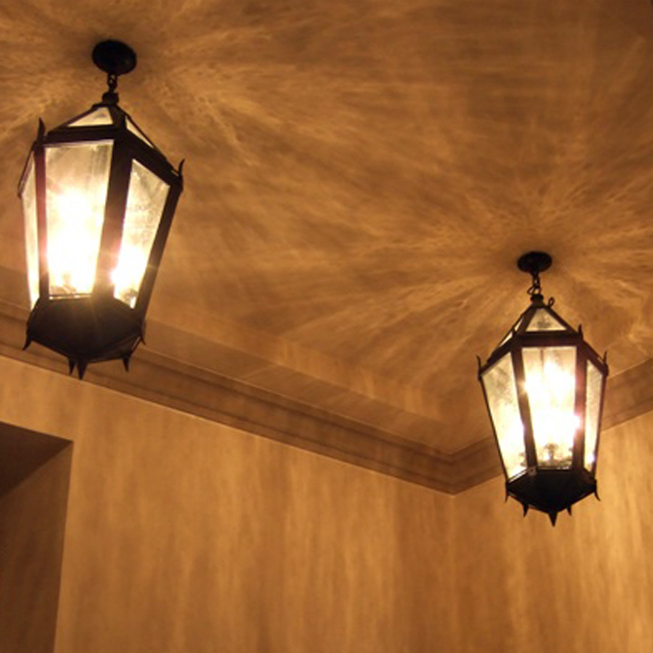 Two hanging lanterns close to each other on ceiling.