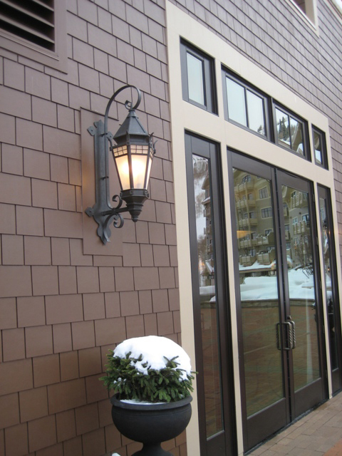 Outdoor gas lantern on brick wall with sliding door to side.