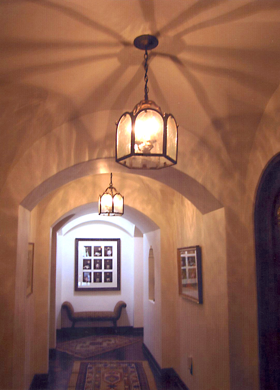 Wrought iron chandeliers hanging from arches in home.